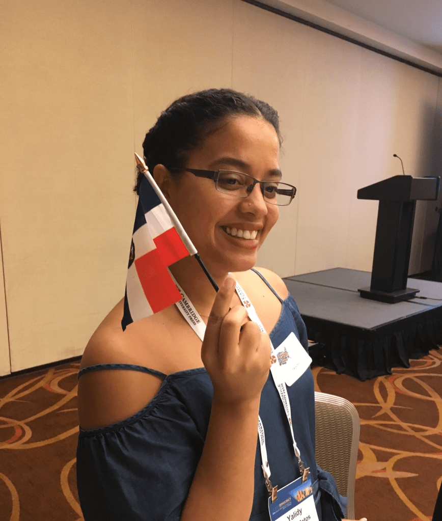 Matos is holding a Dominican flag at a Latino Politics celebration at the Western Political Science Association.